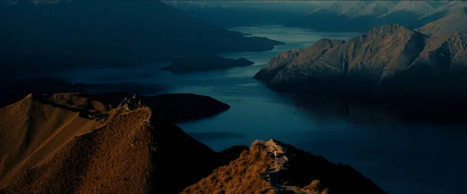 A runner on a ridge above a lake at dusk. Still from ROOTS, Alexis Berg / Little Hell