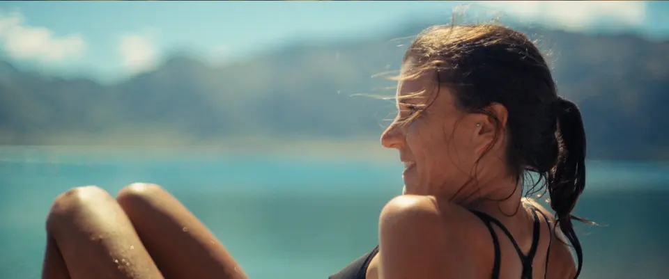 Ruth smiling by a lake. Still from ROOTS, Alexis Berg / Little Hell